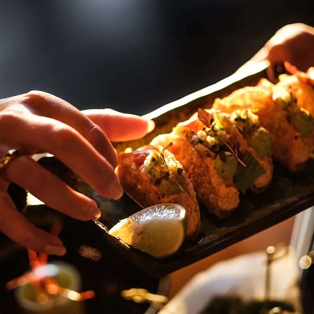Serving a plate of crispy tacos, garnished with fresh lime, in a warm, inviting atmosphere.