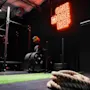 Et knebøystativ og treningsutstyr står ubrukt i et svakt opplyst treningsstudio. Neonskilt lyder "ONE MORE REP". Tykt tau ligger sammenrullet på grønt gress. Industrielt tak synlig.