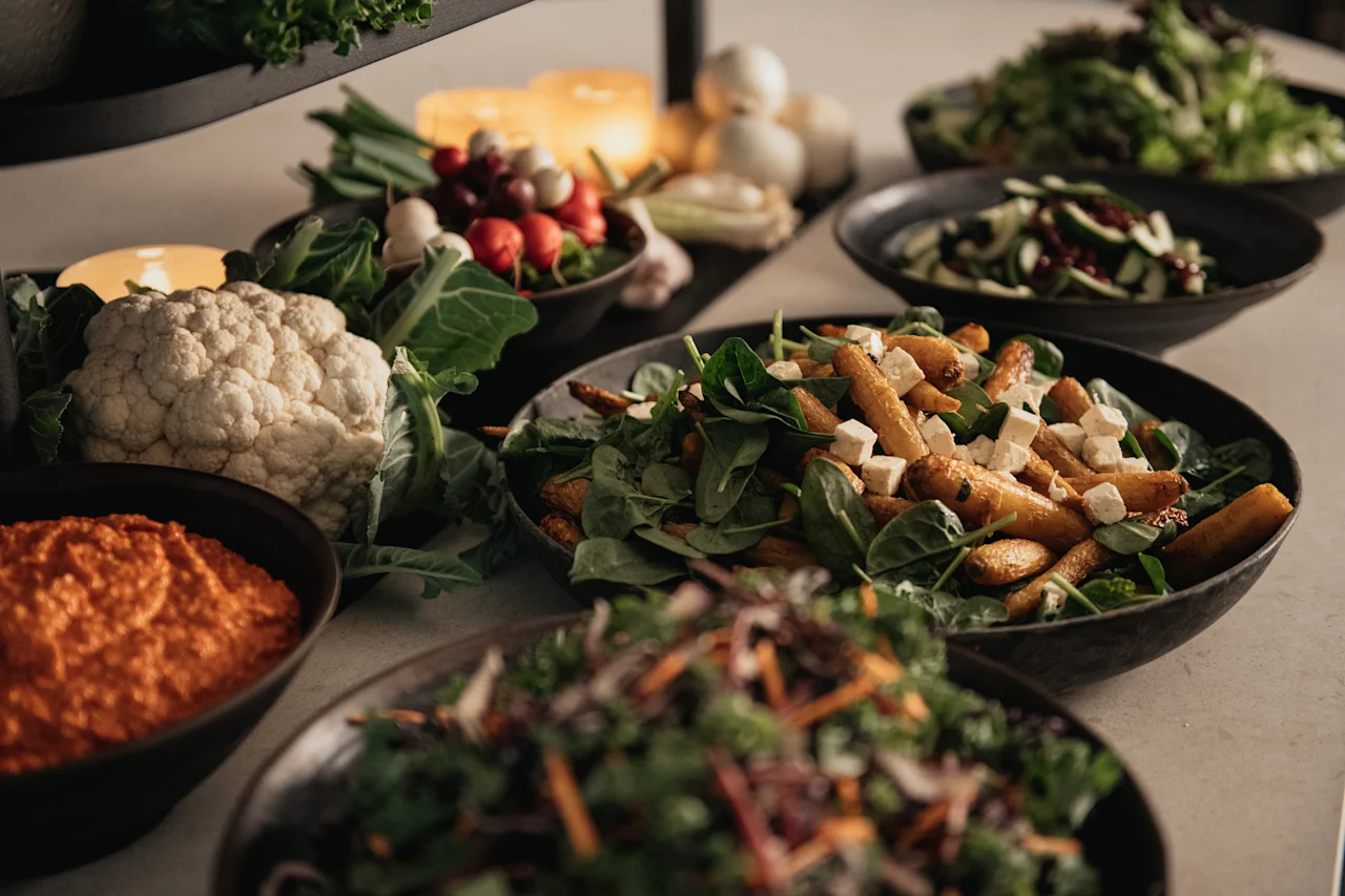 En livlig buffé med fräscha sallader, rostade grönsaker och en krämig dipp, upplyst av mjukt stearinljus.