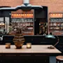Koselig bar eller lounge med trebord, levende lys, murvegger. Tekst: CUBA GIN, OLIVER MARMAR, CHIPS, LAK UP, 145, 115, 30.