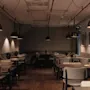 A cozy restaurant dining area with warm lighting from hanging pendant lamps, featuring multiple tables and chairs set for guests.