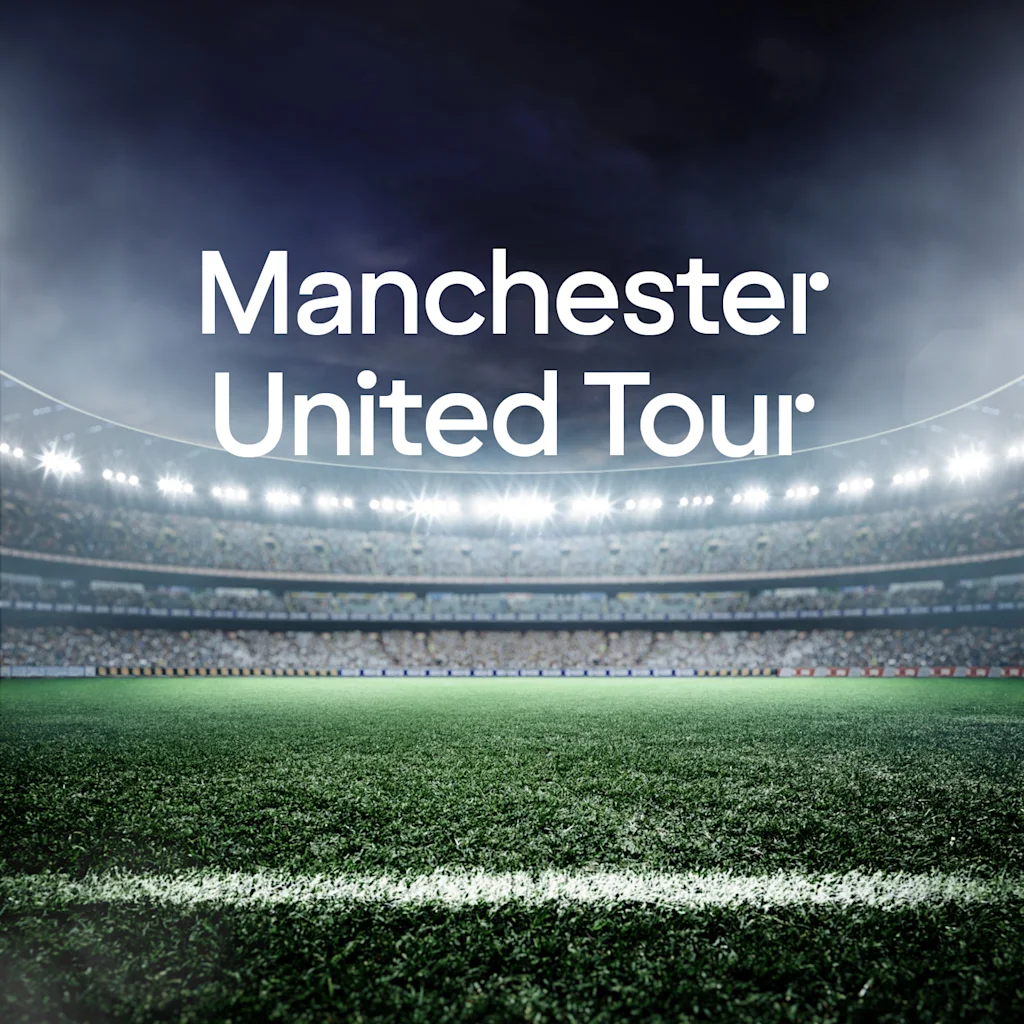 Eloisa jalkapallostadion kirkkailla valoilla ja yleisöllä katsomoissa. Teksti: Manchester United Tour.