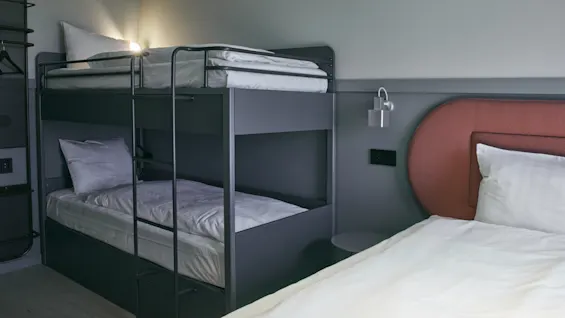 Ett modernt hotellrum på Stopover Hotel Falkenberg med en bekväm våningssäng och en extra enkelsäng, perfekt för familjer.
