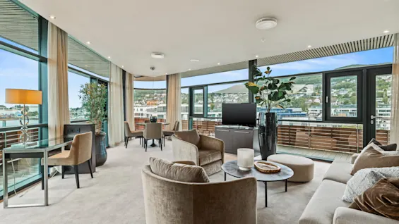 Et moderne og romslig oppholdsrom på Quality Hotel Ulstein med store vinduer, komfortable sitteplasser og en spiseplass.