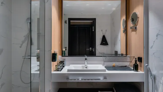 Hotellromsbad med moderne vask, stort speil og glassinnkapslet dusj, som tilbyr et rent og funksjonelt rom.