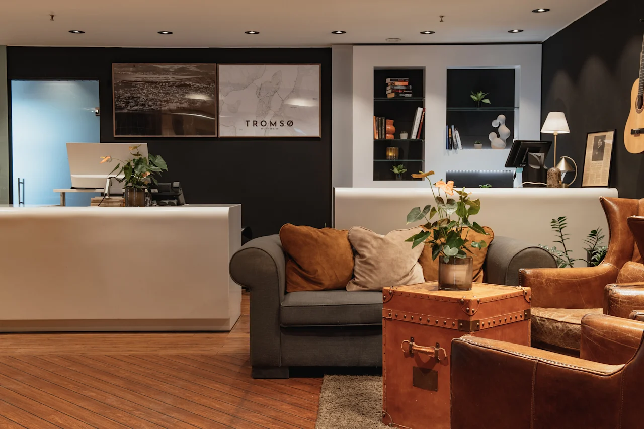 A welcoming hotel lobby featuring a reception desk and a cozy seating area, with 'TROMSO' displayed prominently on the wall.