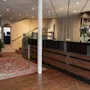 Hotellin vastaanottoalue, jossa on baari, UNGE-merkitty lounge-sisäänkäynti, portaikko ja kuvioitu matto puulattialla.