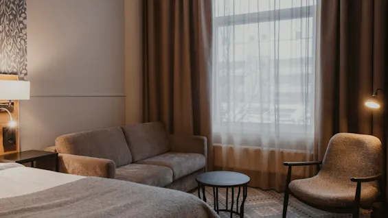 Ett mysigt hotellrum med säng, soffa och fåtölj, som inbjuder till avkoppling och komfort.