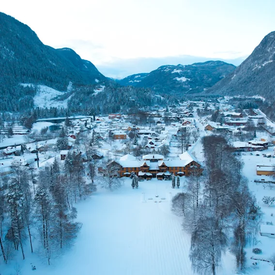 Flyfoto av en snodekt landsby og hotell i en vakker fjelldal om vinteren