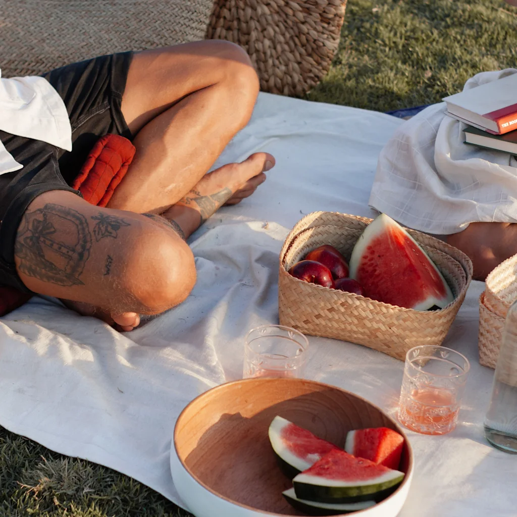 Två personer som njuter av en mysig picknick utomhus på en filt med färsk vattenmelon.