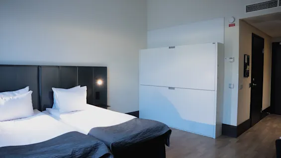 Moderni ja kutsuva hotellihuone Quality Hotel Viewssa, jossa on kaksi mukavaa sänkyä ja tyylikäs valkoinen vaatekaappi.