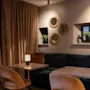 Cozy seating area with dark blue sofa, wooden tables, and warm lighting at Home Hotel Grand Bodø.