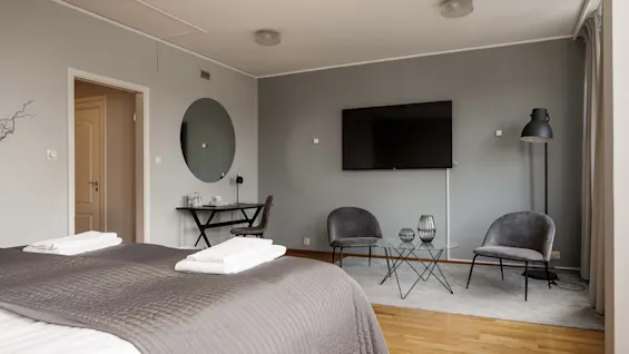 Et moderne hotelværelse med en komfortabel seng, en arbejdsplads og et siddeområde med TV.