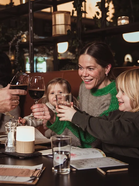 En familj som skålar tillsammans under en trevlig middag på en mysig restaurang.