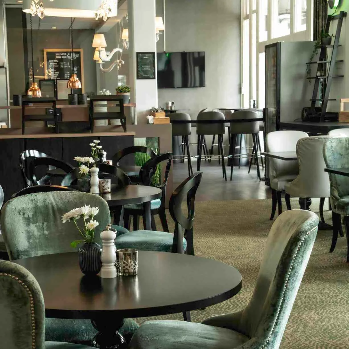 An elegant café with velvet chairs, round tables, and a counter, exuding a vintage charm with modern touches.