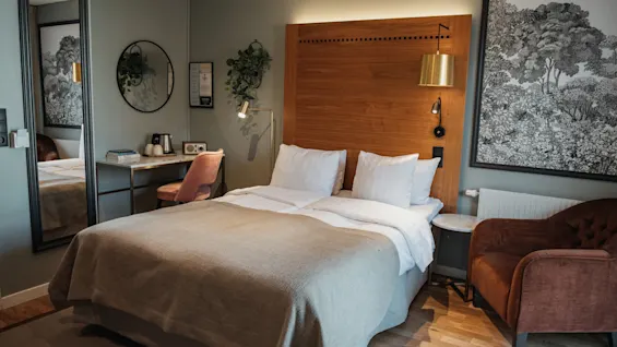 Et hyggeligt hotelværelse med en komfortabel seng, et lille skrivebord og en lænestol, designet til afslapning og arbejde.