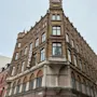 En murbygning med flere etasjer viser ordet "HOTELL" vertikalt på fasaden, og har butikker merket "Mulberry" og "ETON" på bakkeplan.