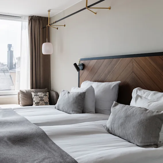 Valoisa ja moderni hotellihuone, jossa kaksi mukavaa sänkyä, työpöytä ja suuri ikkuna kaupunkinäkymällä.