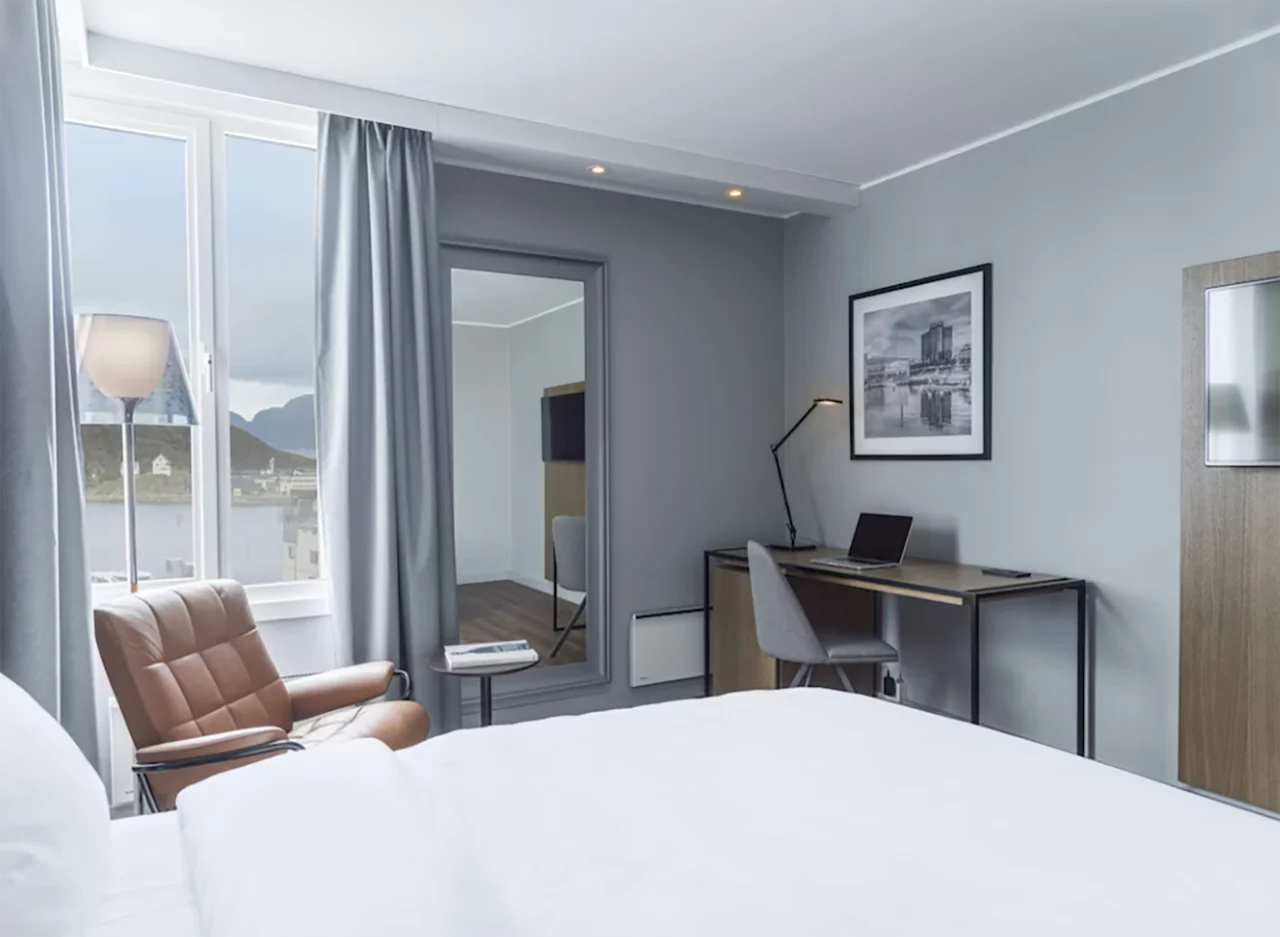 Lyst og moderne hotellrom med skrivebordsplass, lenestol ved vinduet og en behagelig seng.