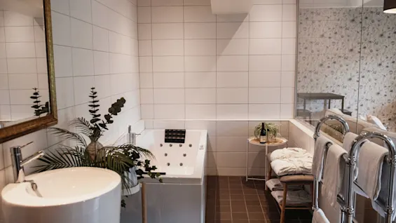 A contemporary bathroom with a large bathtub, a round sink, and lush greenery, offering a tranquil and comfortable retreat.