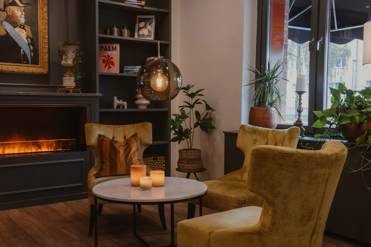 Cozy hotel lounge with armchairs, fireplace, and decorative items. A book titled PALM is visible. Home Hotel Kung Oscar.