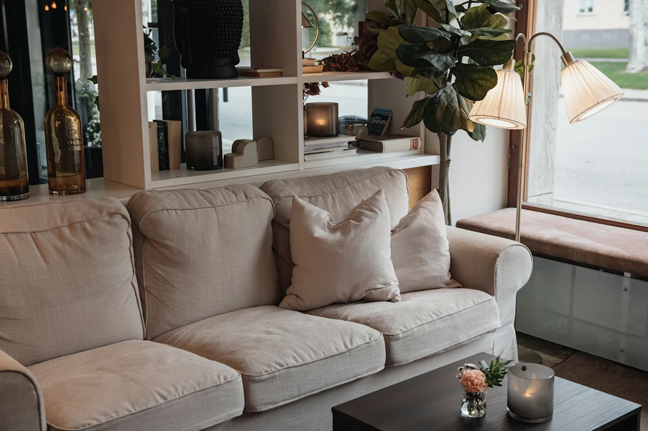 A warm and inviting living space featuring a plush sofa, a coffee table with flowers, and a bookshelf with decor.