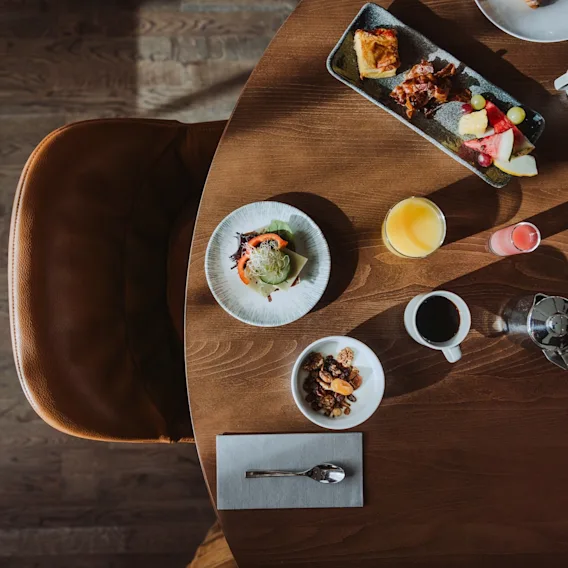 En härlig frukostuppdukning på ett träbord med olika rätter, juicer och kaffe, redo att avnjutas.