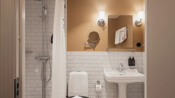 Home Hotel Baltzar - Junior Suite. A clean and well-lit bathroom with a shower, toilet, and sink, ready for use.