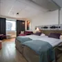 Perhehuone neljälle hengelle Quality Hotel Grand Tromsøssa, jossa on kaksi sänkyä, sohva ja mukava oleskelutila.