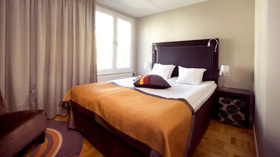 Standard dubbel med dubbelsäng, nattduksbord, fåtölj och fönster på Home Hotel Tapto i Stockholm