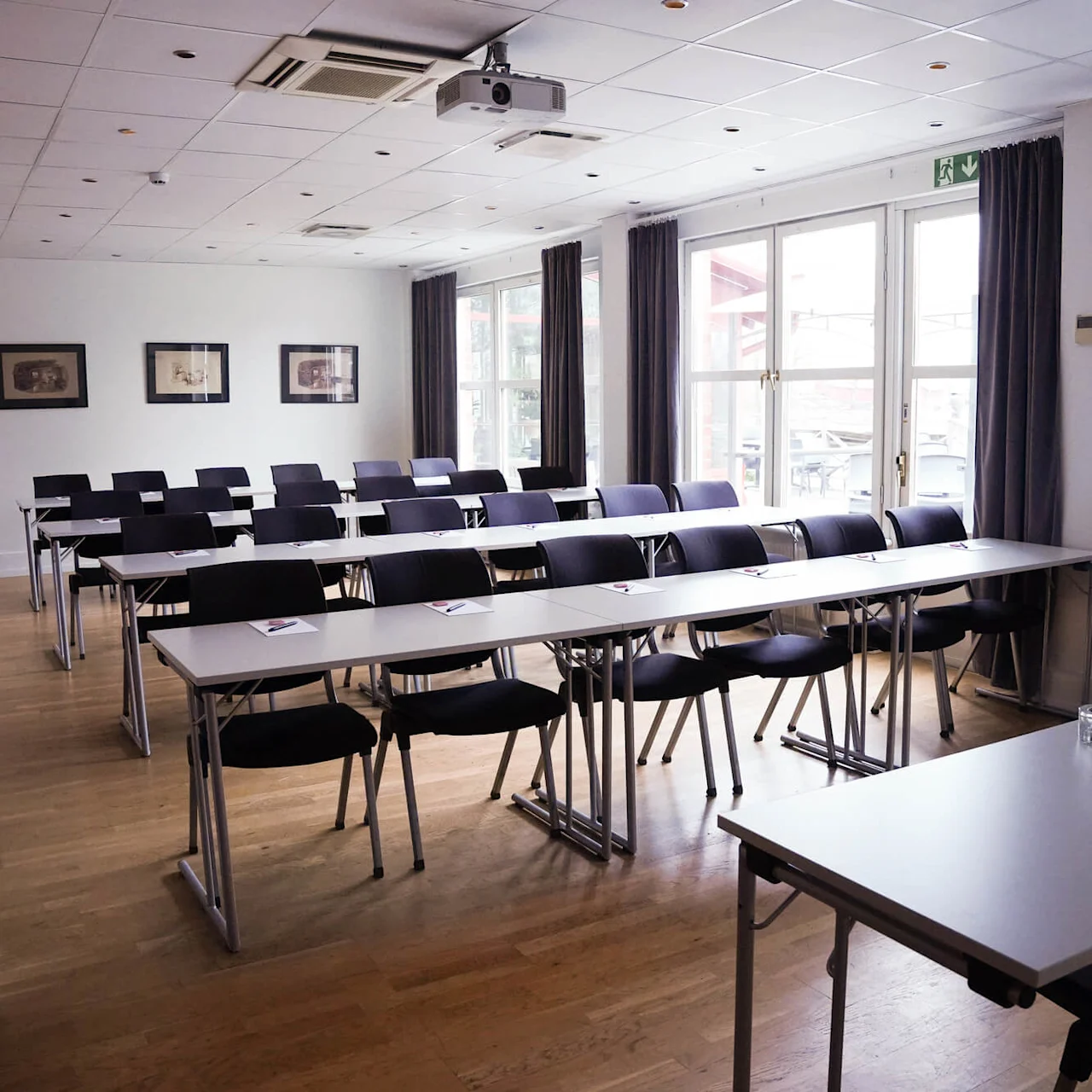 Empty meeting room with rows of tables and chairs, ready for attendees, in a bright modern interior. 