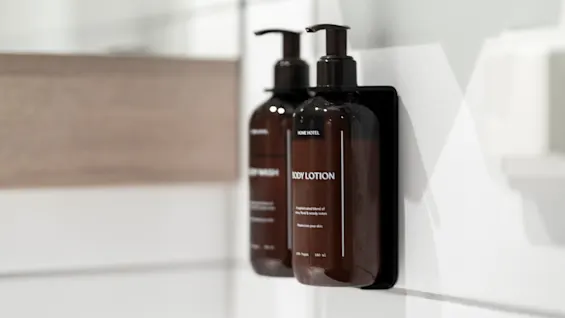 To pumpeflasker, en merket Body Lotion og den andre Body Wash, montert på en hvit flislagt vegg.