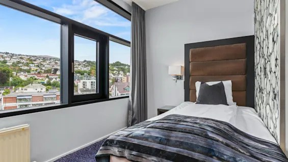 Ett mysigt rum på Quality Hotel Ulstein med en bekväm säng och ett stort fönster med utsikt över en naturskön stad.