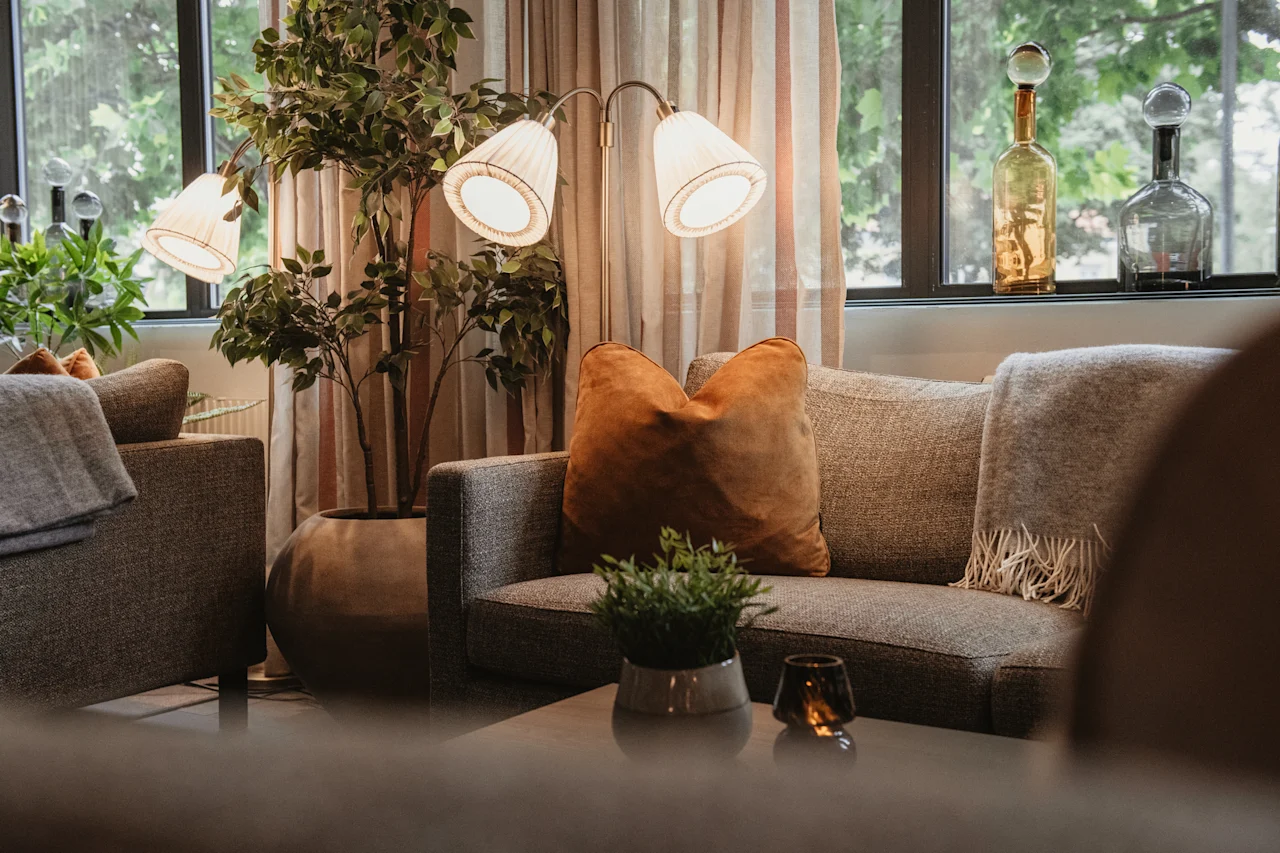 A warm and inviting living space featuring a comfortable sofa with pillows and a throw, illuminated by a stylish floor lamp.