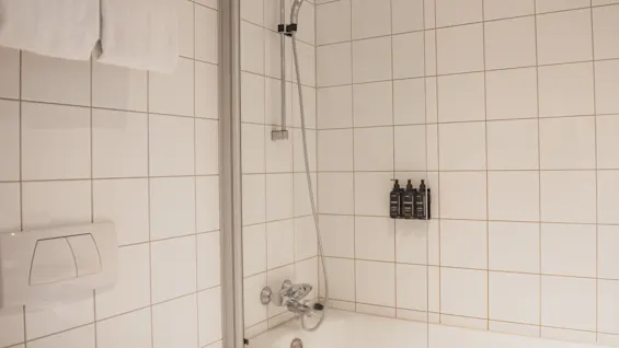 Ett välutrustat badrum med badkar, dusch och kostnadsfria toalettartiklar, redo för en uppfriskande tvätt.