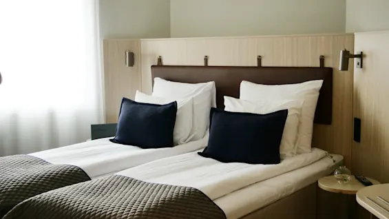 Et komfortabelt hotellrom på Quality Hotel Arlanda XPO med to pent oppredde senger, klart for et avslappende opphold.