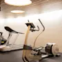 Ett modernt gym med en crosstrainer märkt EXCITE och ett löpband, redo för ett träningspass.