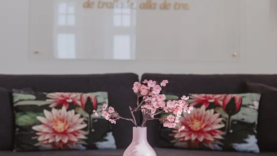 Olohuone, jossa on sohva, sohvapöytä ja seinäpaneeli, jossa on ruotsalainen runo. Se alkaa: Dar gingo tre jantor i solen.