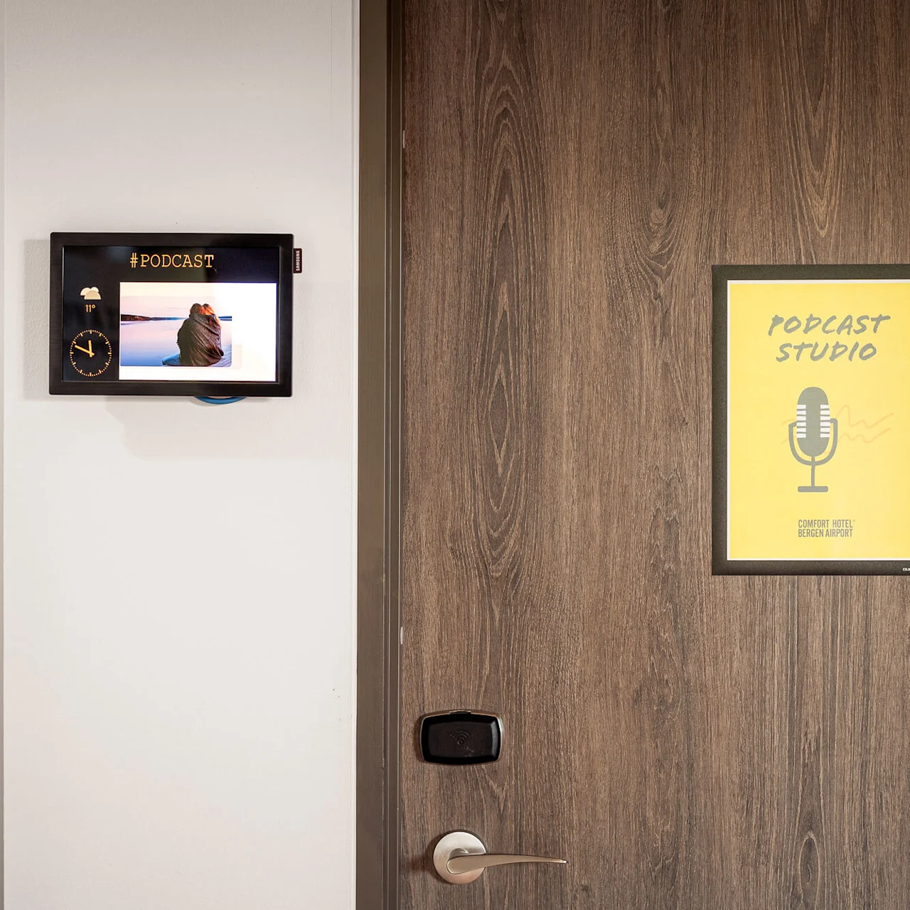 A small screen displays a podcast-related image and "#PODCAST", next to a wooden door labeled "PODCAST STUDIO" with a microphone symbol. Wall text: "-Unknown".