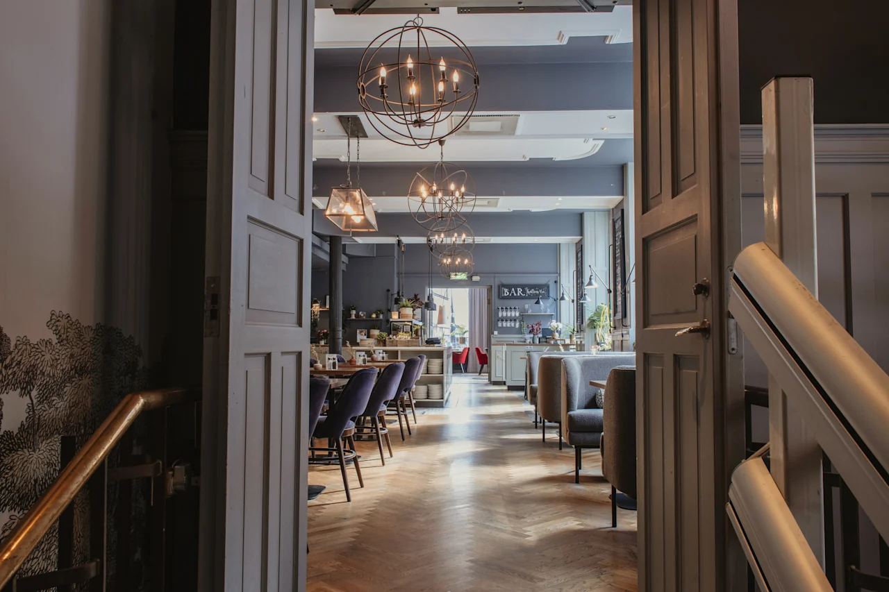 Et innbydende hotellrestaurant- eller barområde med stilige sitteplasser, varm belysning og et synlig BAR-skilt.