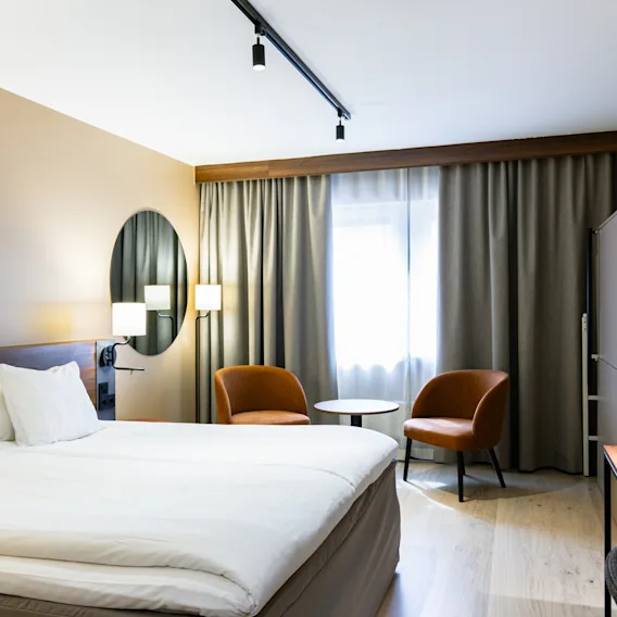Bright and modern hotel room with a double bed and two armchairs at Clarion Hotel Winn.