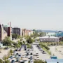Ilmakuva vilkkaasta kaupungista, jossa on suuri pysäköintialue, historiallisia rakennuksia ja satama etäällä.