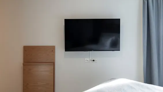 A comfortable room with a television and a space-saving desk, perfect for unwinding or getting things done.