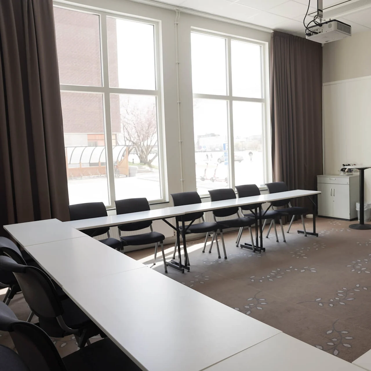 Ett konferensrum med ett långt bord, stolar och presentationsutrustning, vilket antyder en arbets- eller utbildningsmiljö.