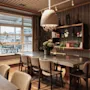 An elegant dining or meeting room featuring a long wooden table, comfortable chairs, and a large window overlooking a scenic view.