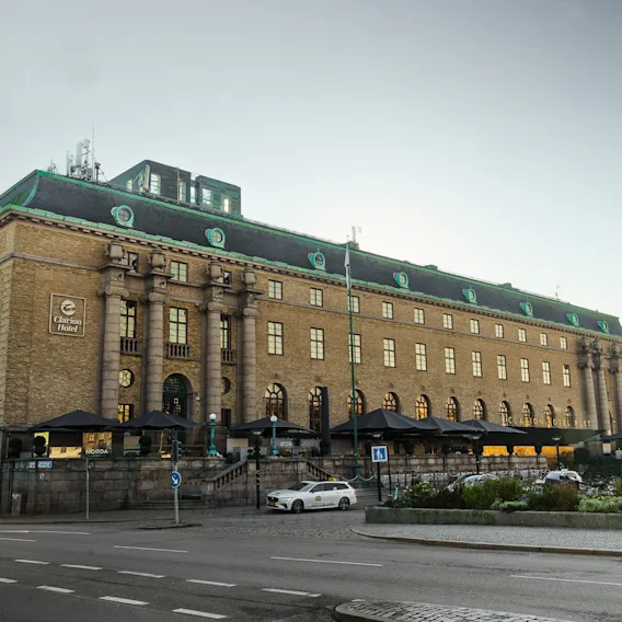 Exteriör vy av Clarion Hotel Post, en ståtlig byggnad med grönt tak och uteserveringar, intill en gata.