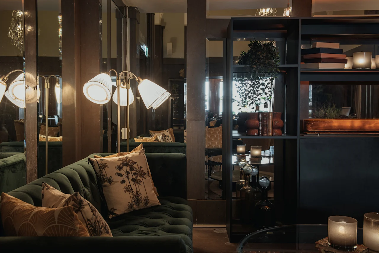 Inbjudande lounge på Home Hotel Grand, Helsingborg, med en plyschgrön soffa, varm belysning och elegant inredning för avkoppling.