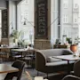 Et innbydende restaurantinteriør med ulike sitteplasser og store vinduer. Krittavler viser menyer for Rott Vin og vitt vin.