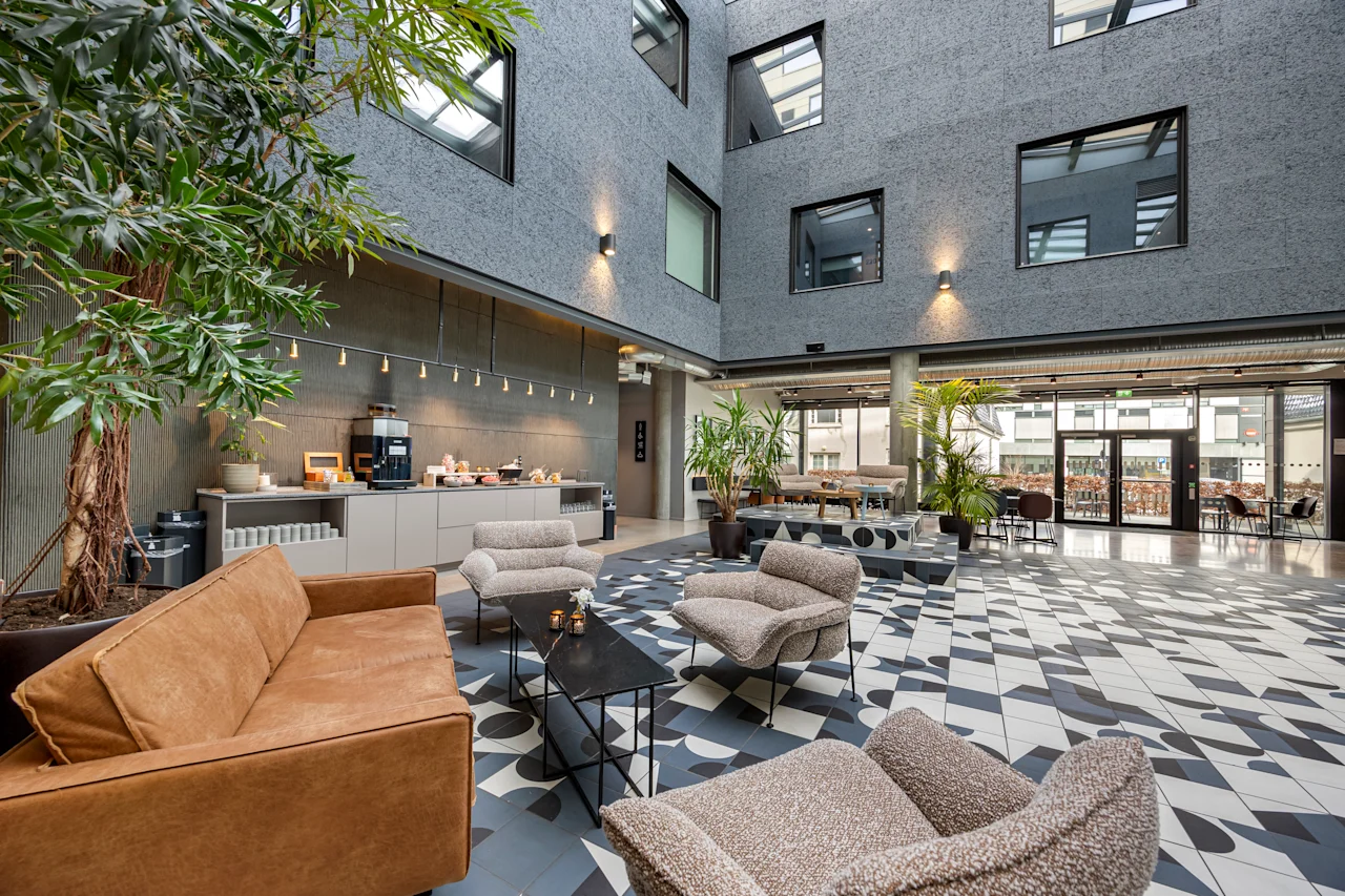 Moderne og innbydende lobby på Comfort Hotel Porsgrunn med komfortable sitteplasser, planter og forfriskningsstasjon.