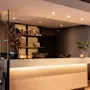 Et indbydende hotelreceptionsområde med en lyst oplyst skranke, computere og elegant indretning inklusive planter og stearinlys. Synlig etiket: PAPER.